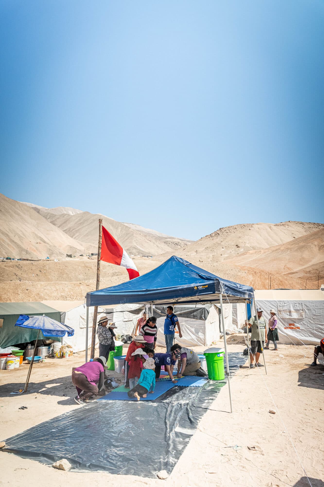 A CADENA relief camp with tents and the Peruvian flag in the desert near Secocha