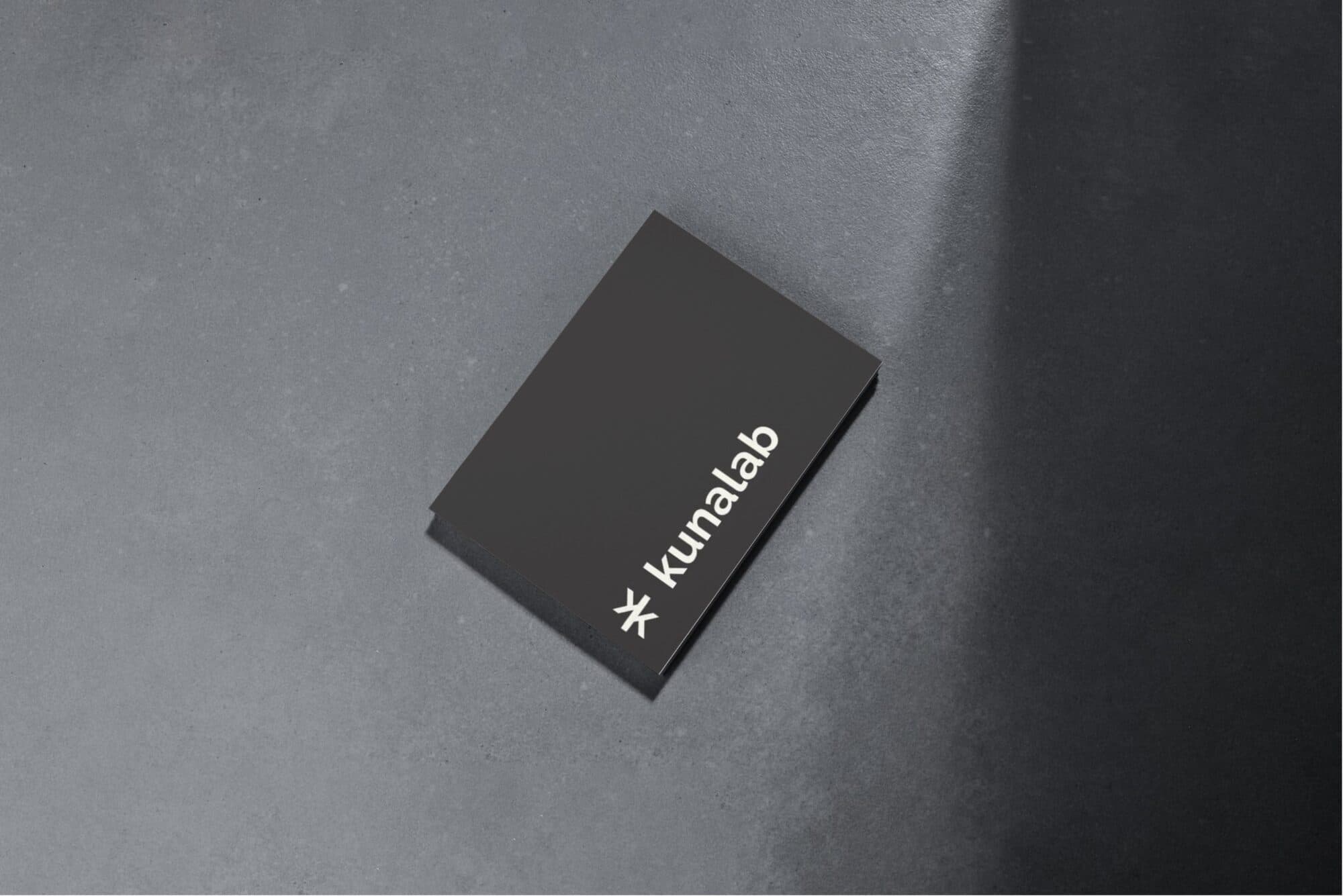 The matte black Kunalab business card photographed on concrete
